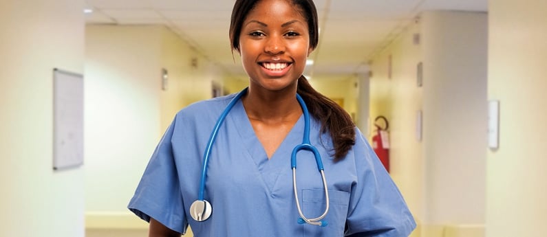 Close up of a nurse in a medical building hallway. She has a stethoscope around her neck. 