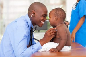 Medical assistant examining baby boy