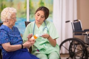 Medical Assistant Explains Medication To Elderly Patient