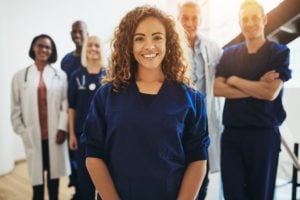 Medical Assistant Stands In Front of Coworkers