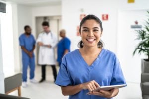 Smiling nurse uses tablet in hospital