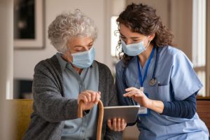 Medical Assistant Using Tablet With Elderly Woman