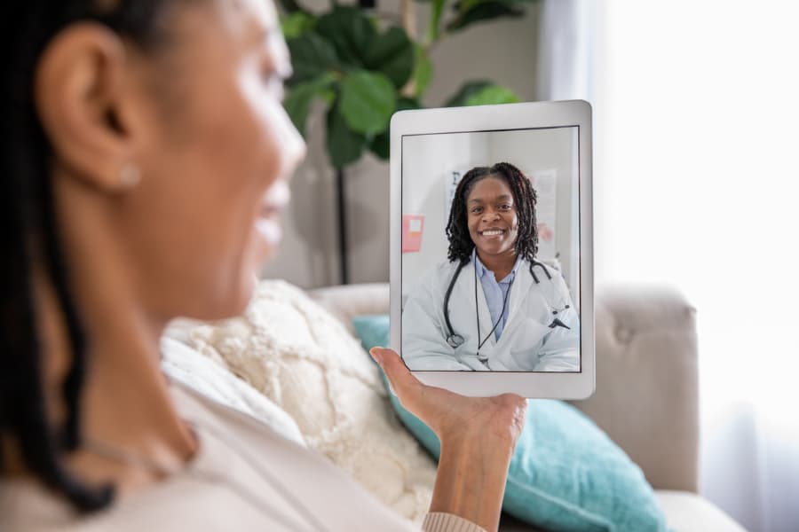 Homebound patient smiles at the screen as medical assistant introduces telehealth appointment 