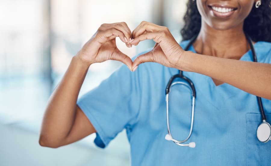 Close up of smiling nurse making a heart shape with her hands in hospital
