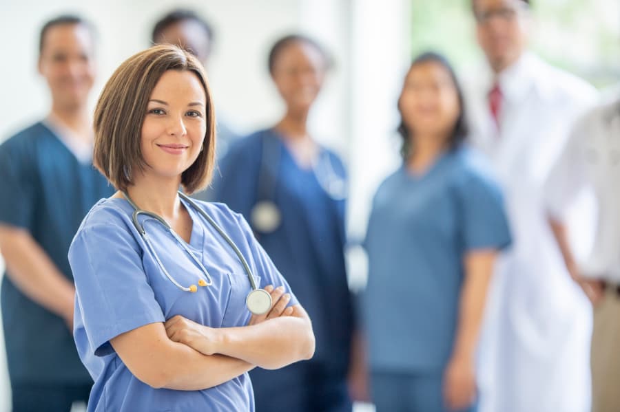 Medical assistant standing in front of rest of medical team in healthcare facility 