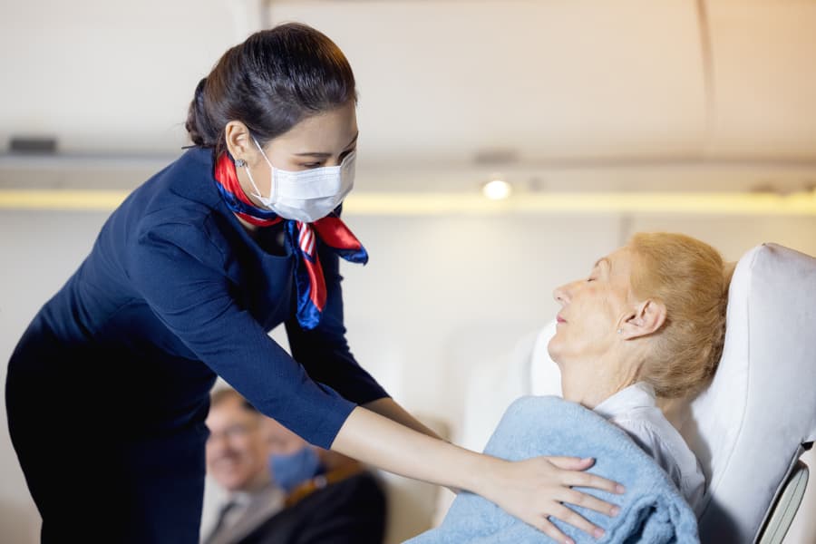 Nurse with mask checks on dozing patient on airplane